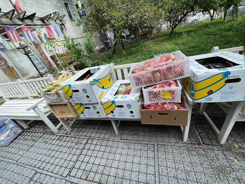 Tables lined with produce and boxed groceries before neighborhood distribution begins